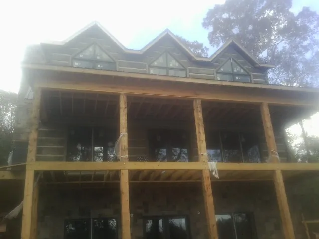 Dormers and porch framing on a large log home under construction — Roof Coating work by our crew in Shorewood