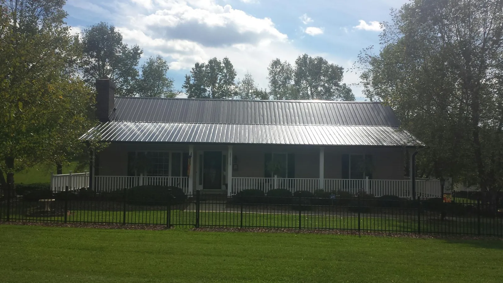 Gray metal roof on a brick ranch with a full width front porch — Gutter Guard Installation work by our crew in Shorewood
