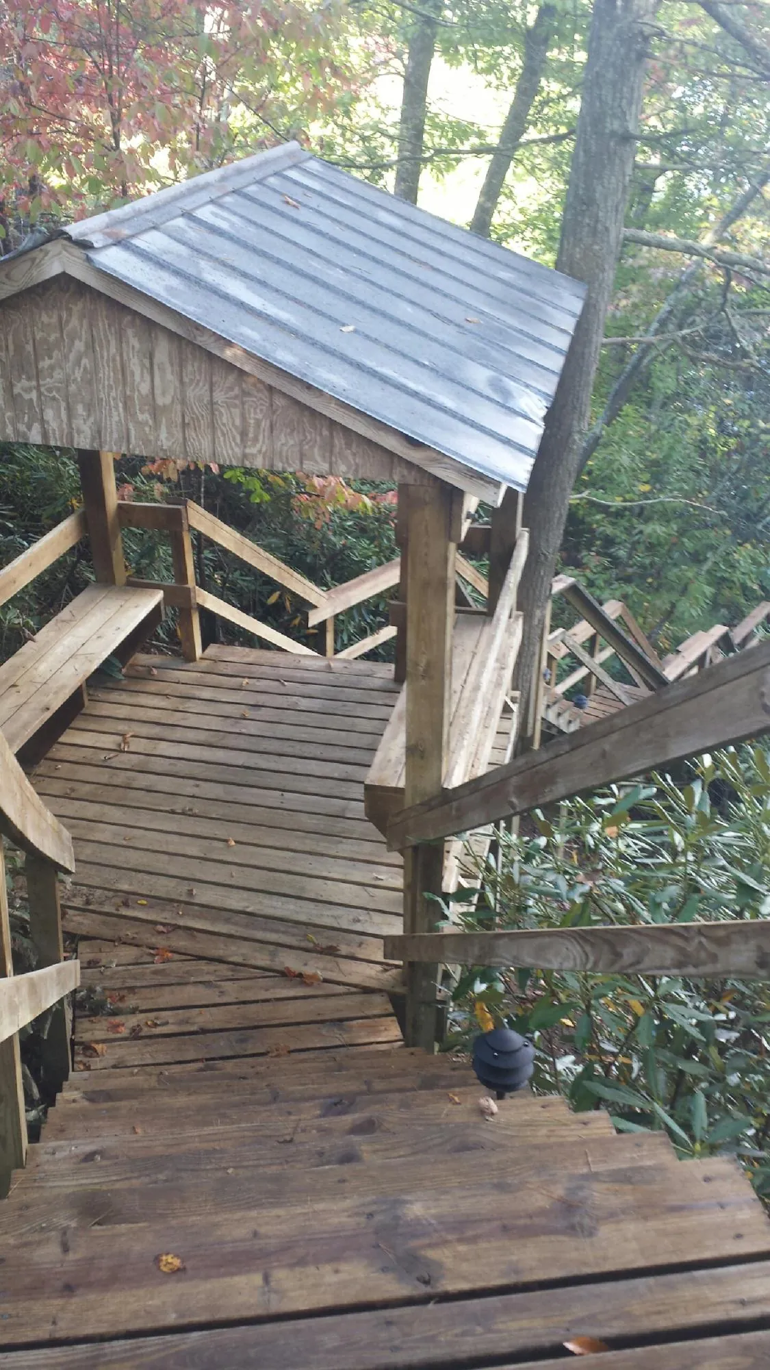 Metal roofed shelter over wooden steps on a wooded walkway — Skylight Repair & Installation work by our crew in Shorewood