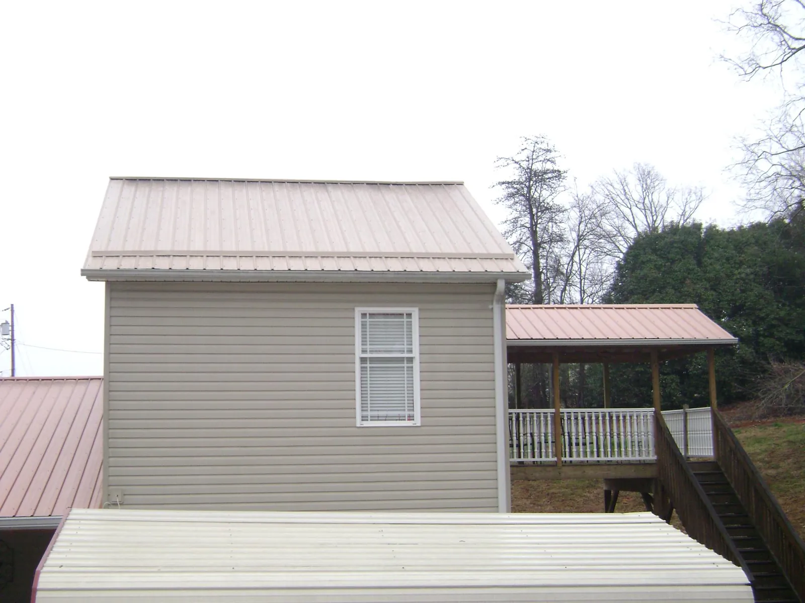Tan metal roofs on a two story addition and attached porch, from a Roof Replacement job in Shorewood
