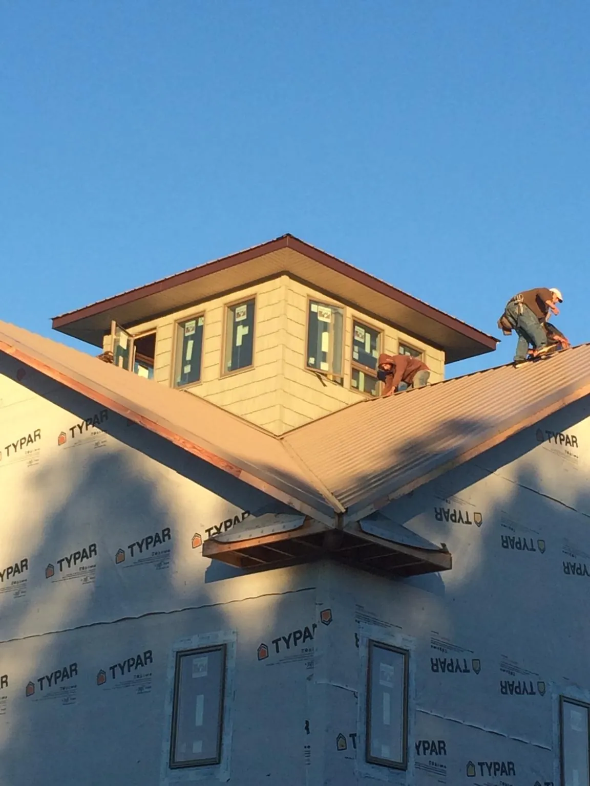 Roofers working around a rooftop cupola on a new metal roof at sunset — Roof Waterproofing in Shorewood by Roofing Brothers